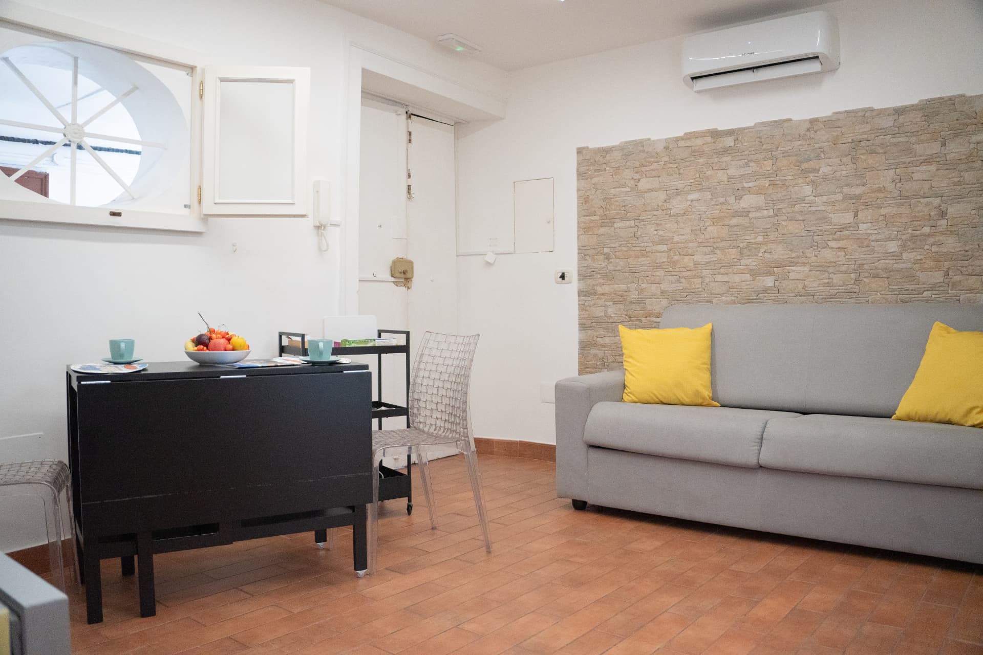 Zona pranzo con tavolo nero, sedie e divano nell'area living del Salotto Plebiscito