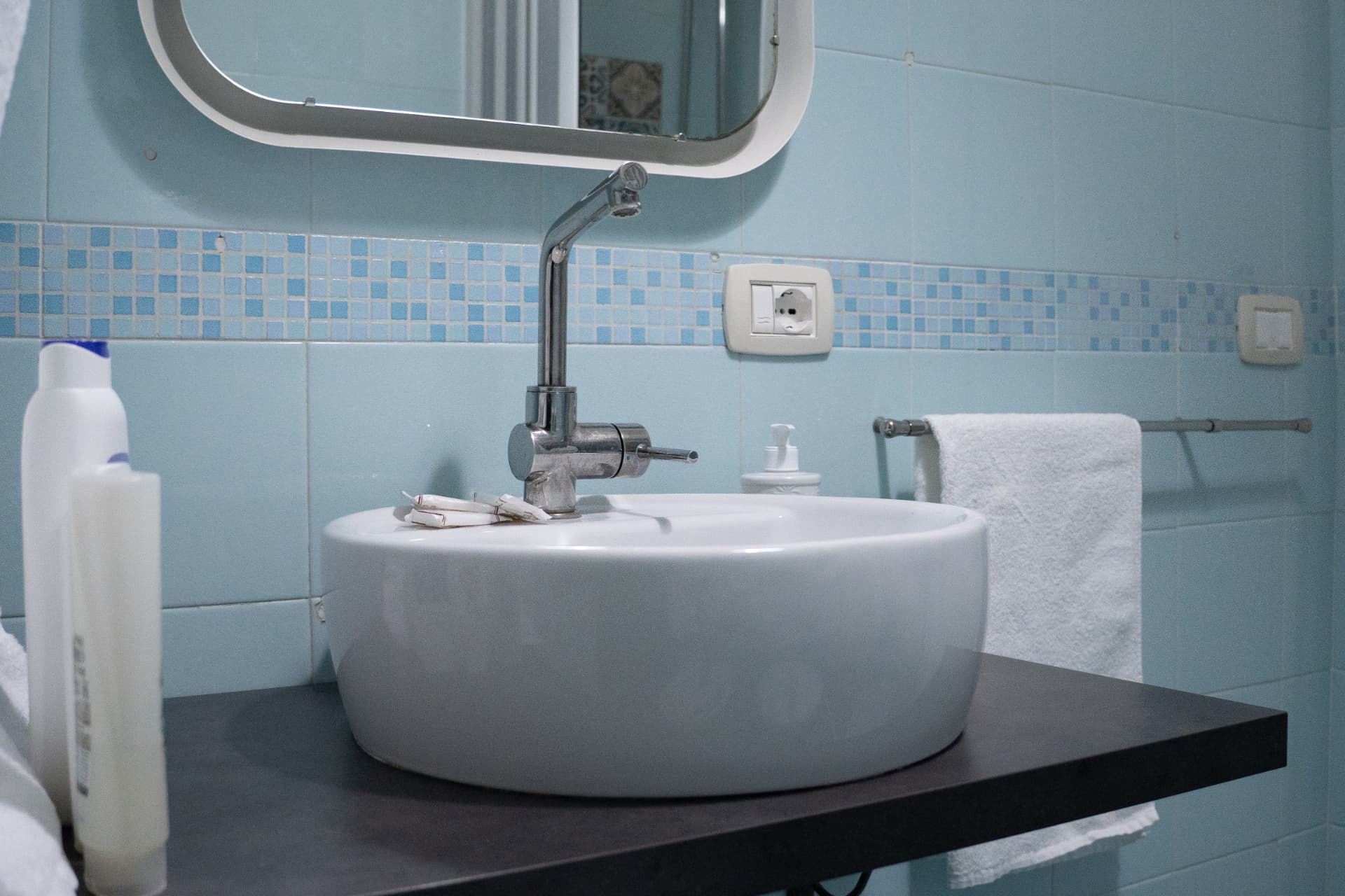 Bagno privato con lavabo tondo e piastrelle azzurre